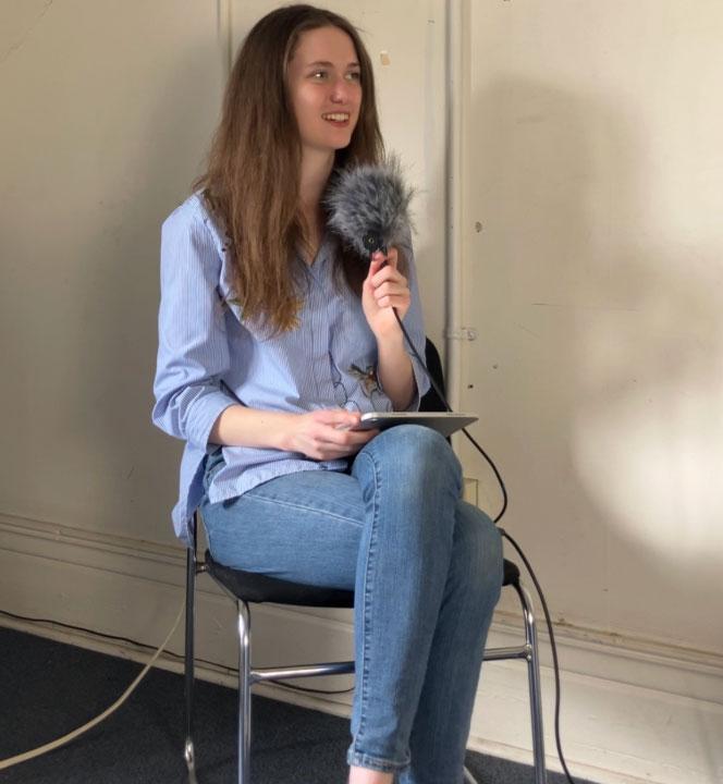 Maeve Ellis holds a microphone; she now reports for CBC Saskatchewan.